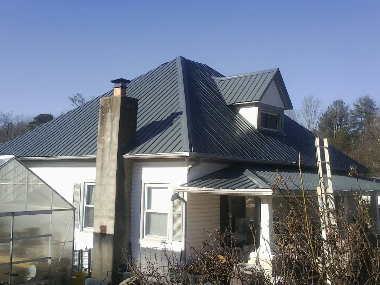 Dark blue standing seam metal roof on a white farmhouse with dormer — Slate & Tile Roof Repair by Roofing Brothers in Offutt Afb