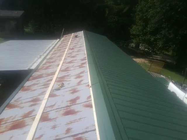Old rusted panels beside newly installed green metal roofing — Wind Damage Roof Repair by Roofing Brothers in Offutt Afb