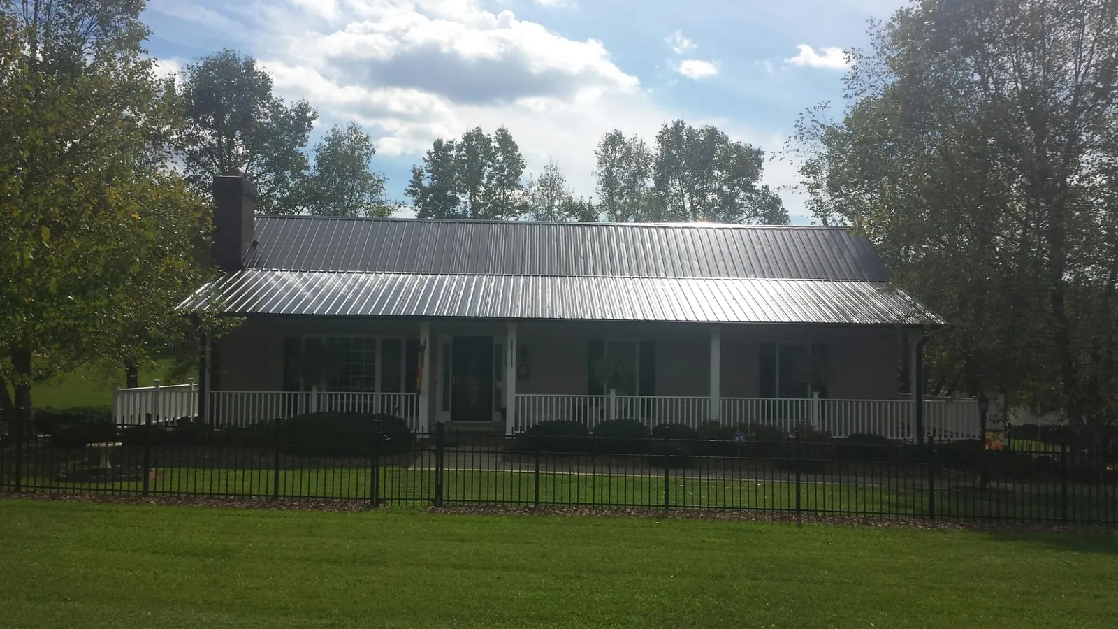 Gray metal roof on a brick ranch with a full width front porch — Gutter Guard Installation work by our crew in Offutt Afb
