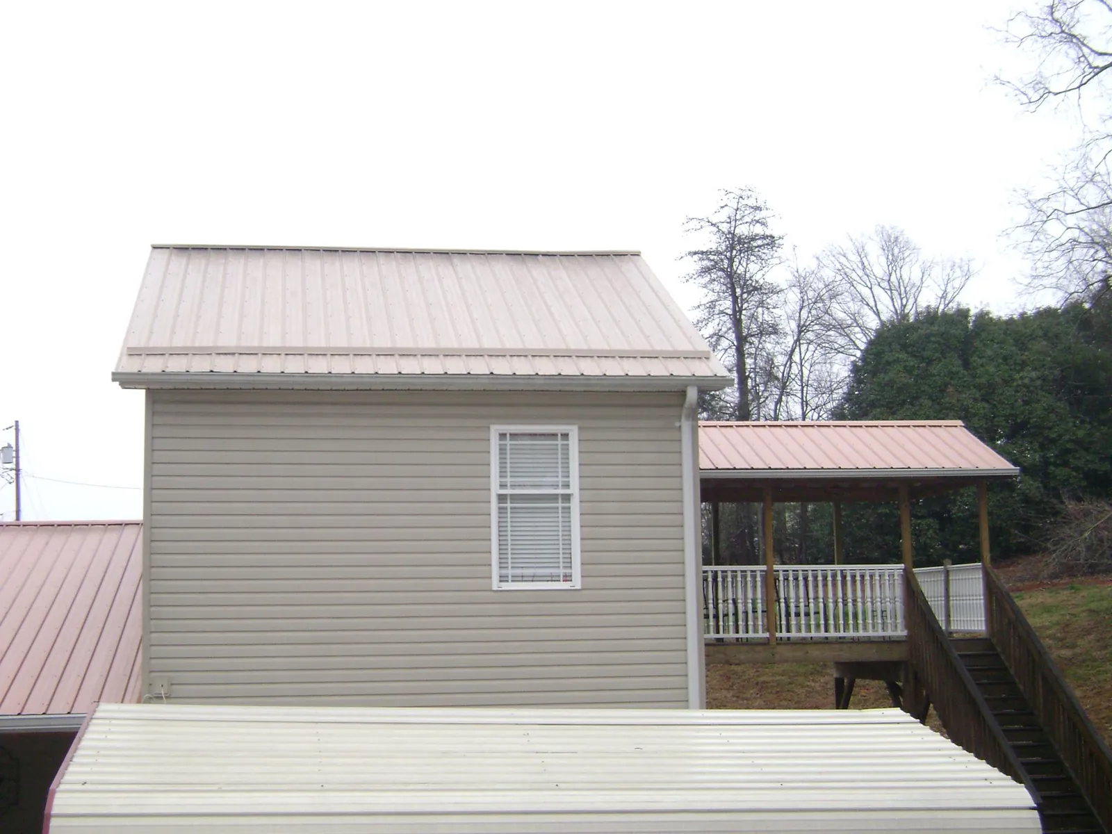 Tan metal roofs on a two story addition and attached porch, from a Roof Replacement job in Offutt Afb